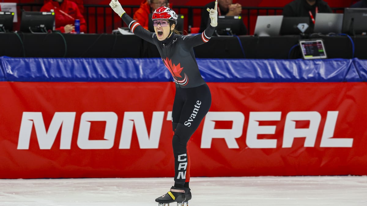 Speed skater with arms raised in the air, appearing to celebrate.