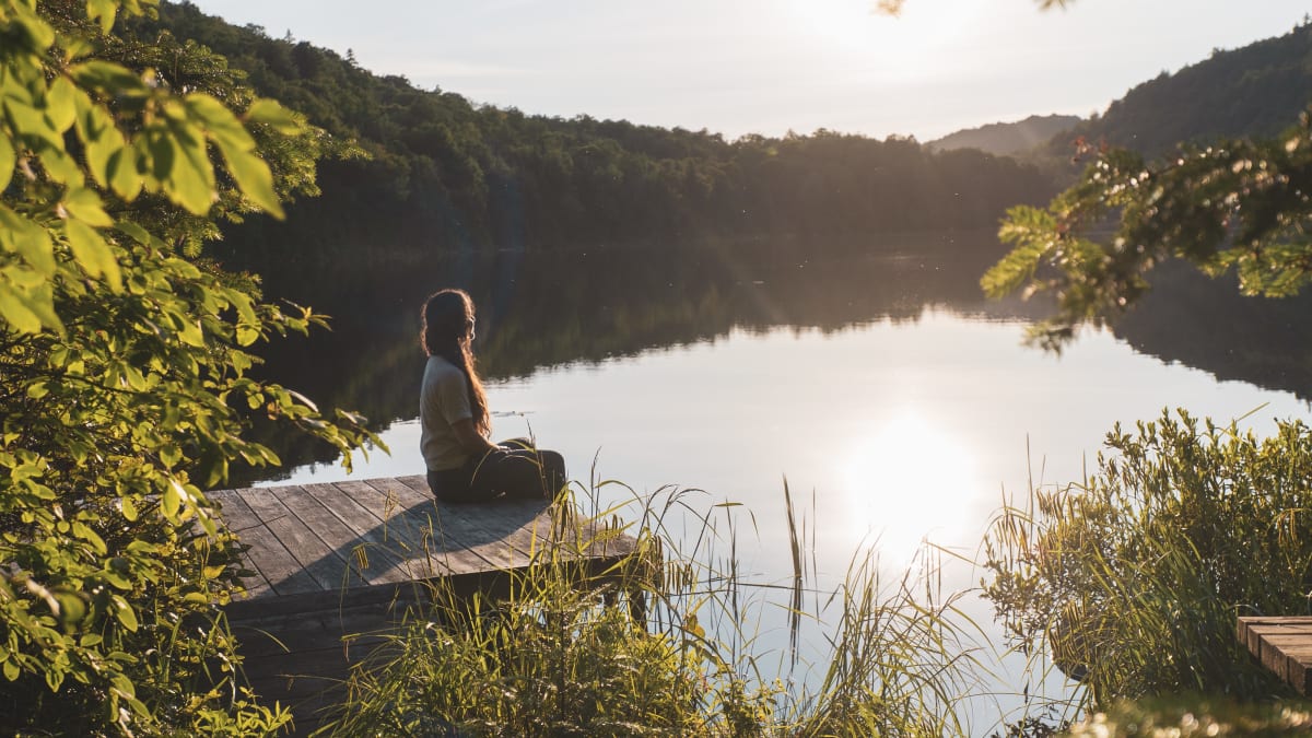 Femme en position du lotus au bord d'un quai dans les Laurentides.