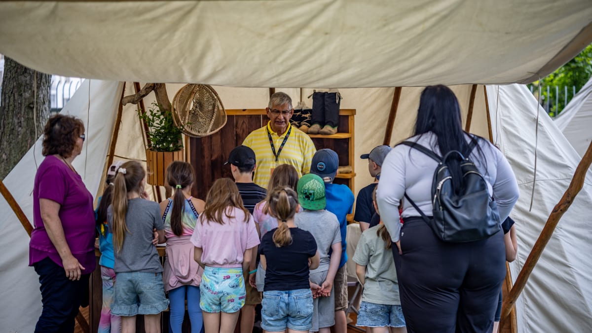 Kids and adults at a booth of Indigenous merchandise.