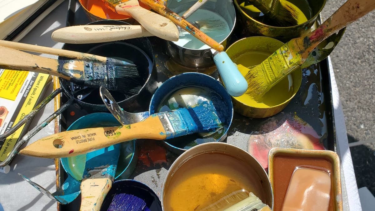 Several open paint containers with brushes.
