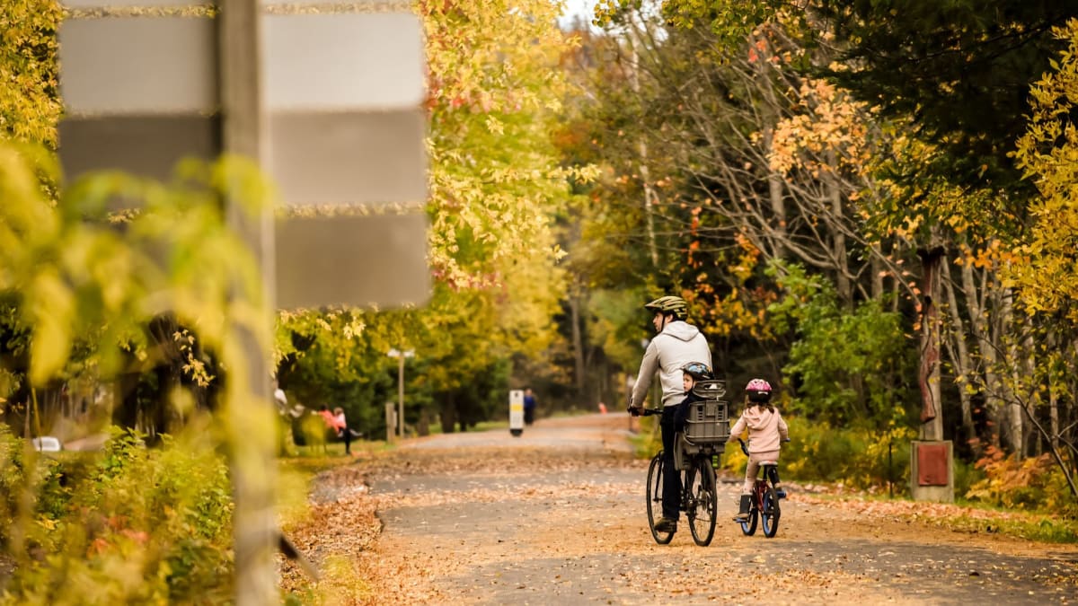 Père et deux enfants en vélo sur le Parc linéaire le P'tit Train du Nord.