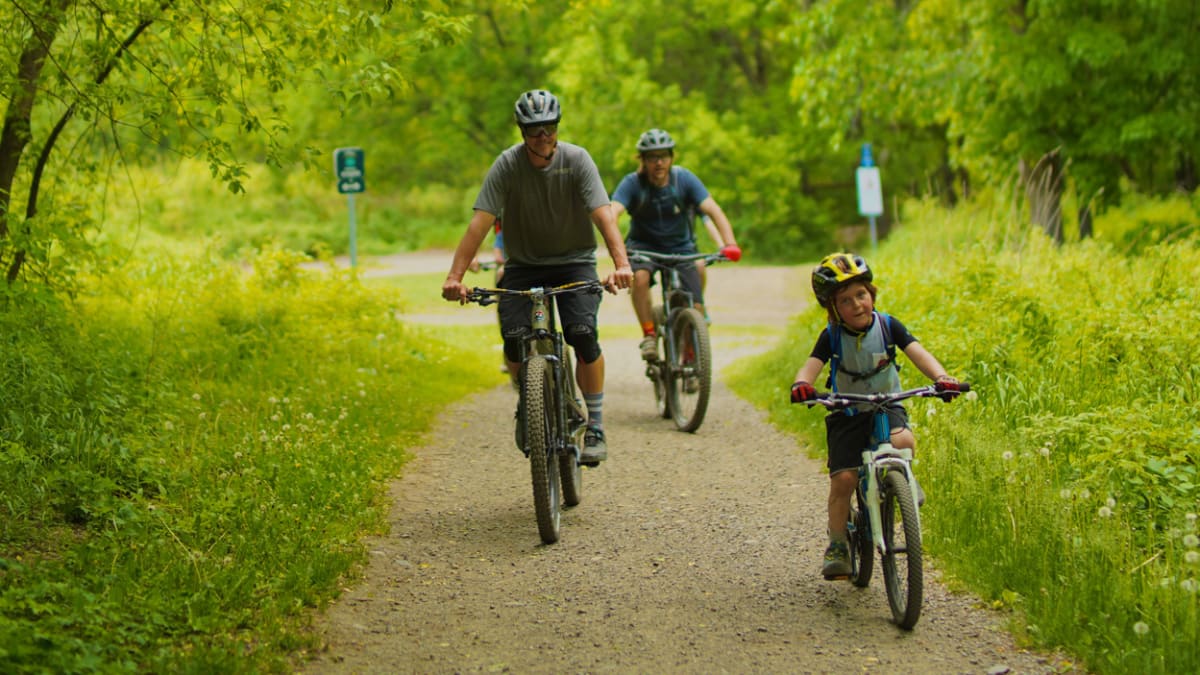 Famille de 3 en vélo sur une piste en forêt.
