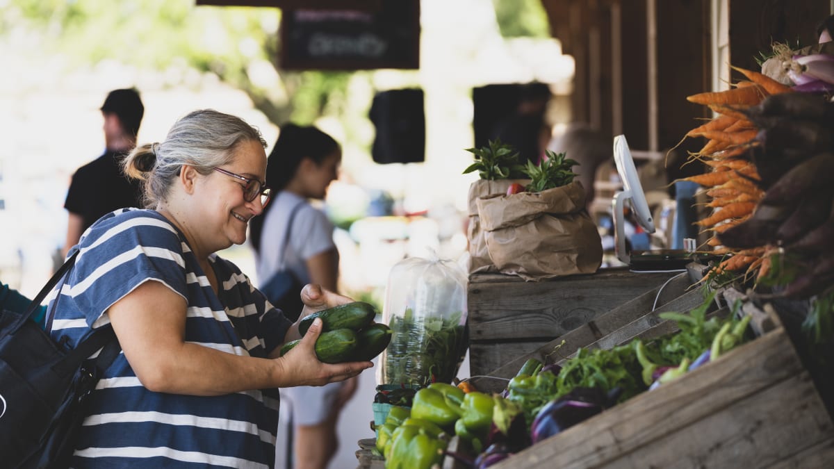 Femme au marché qui achète des légumes