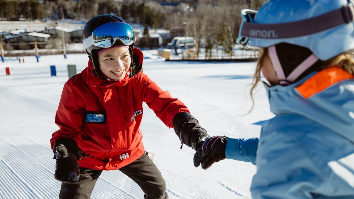 Monitrice tout sourire avec un élève sur les pistes.