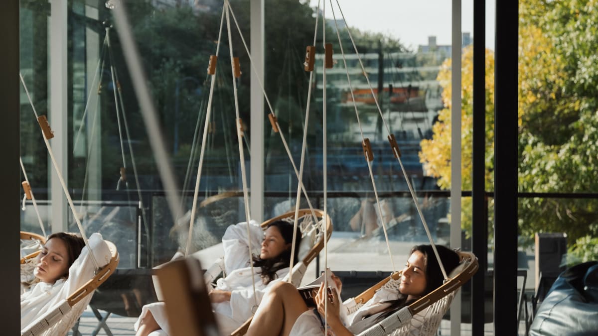 3 jeunes femmes sur la terrasse du spa dans des chaises-balançoires suspendues.