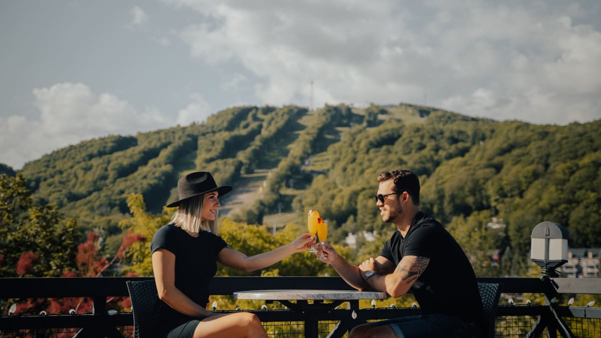 Couple sharing a drink in front of the ski hill in late summer.