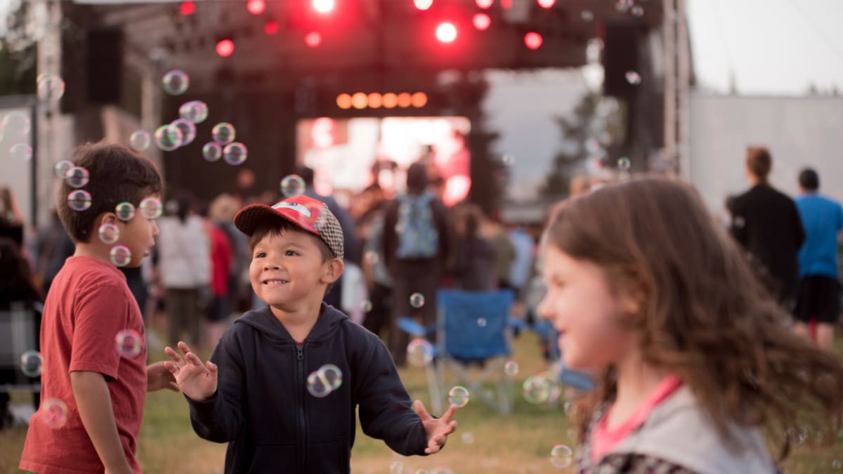 3 enfants qui s'amusent devant la scène au festival.