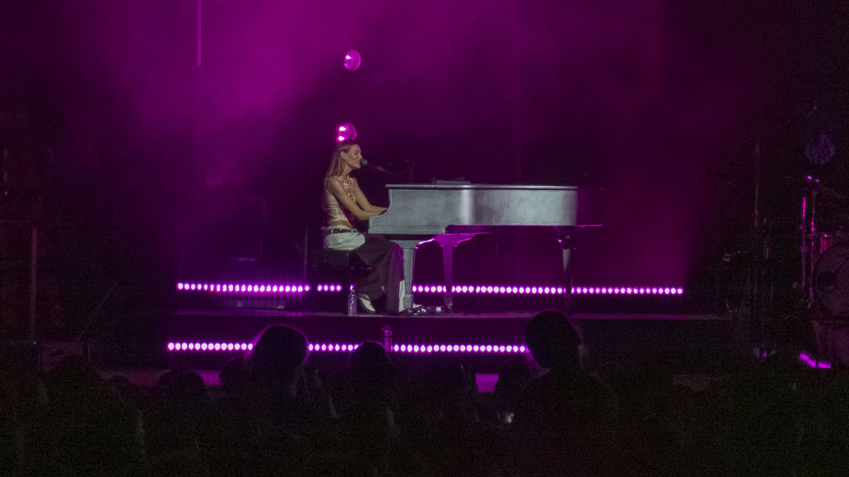 Charlotte Cardin at the piano on stage in the evening.
