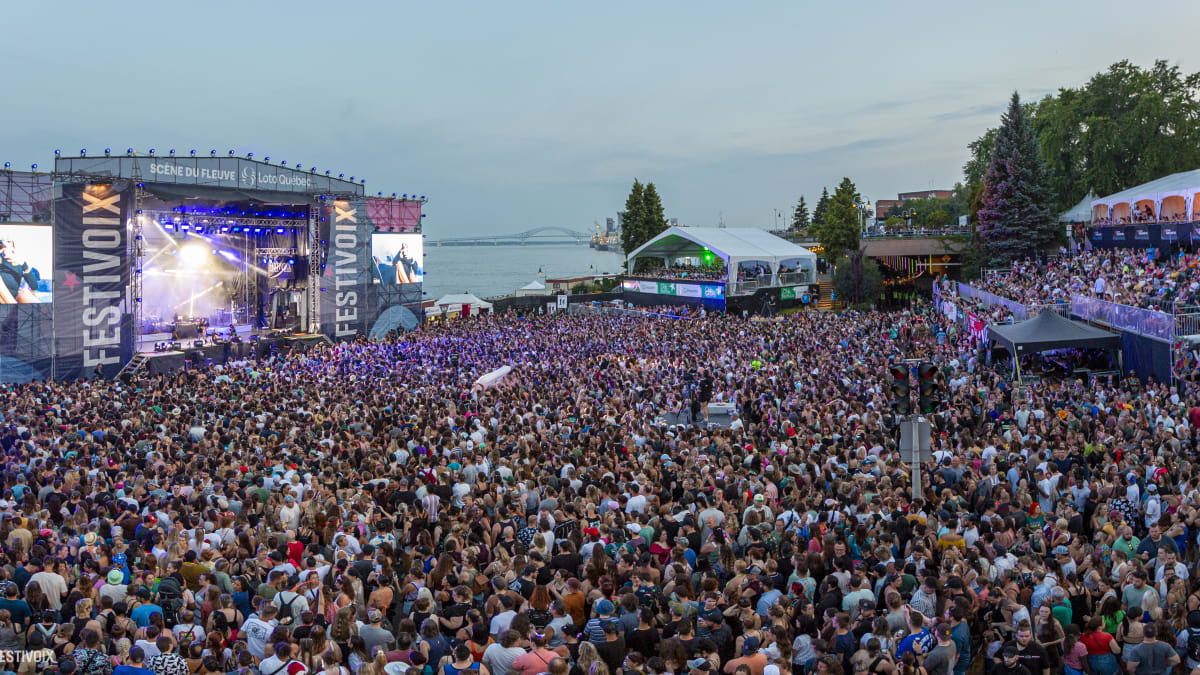 A dense crowd in front of a stage by the St. Lawrence River.