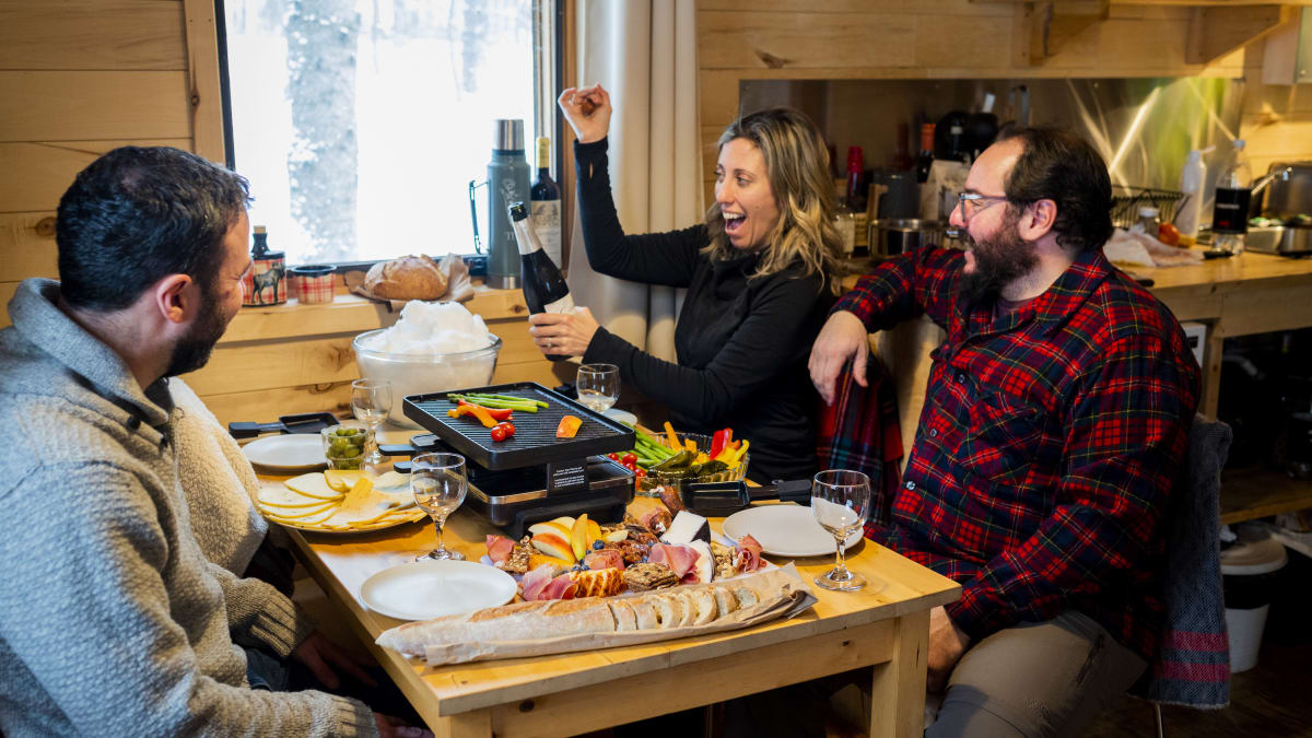 Deux couples attablés pour savourer une raclette et une bouteille de vin