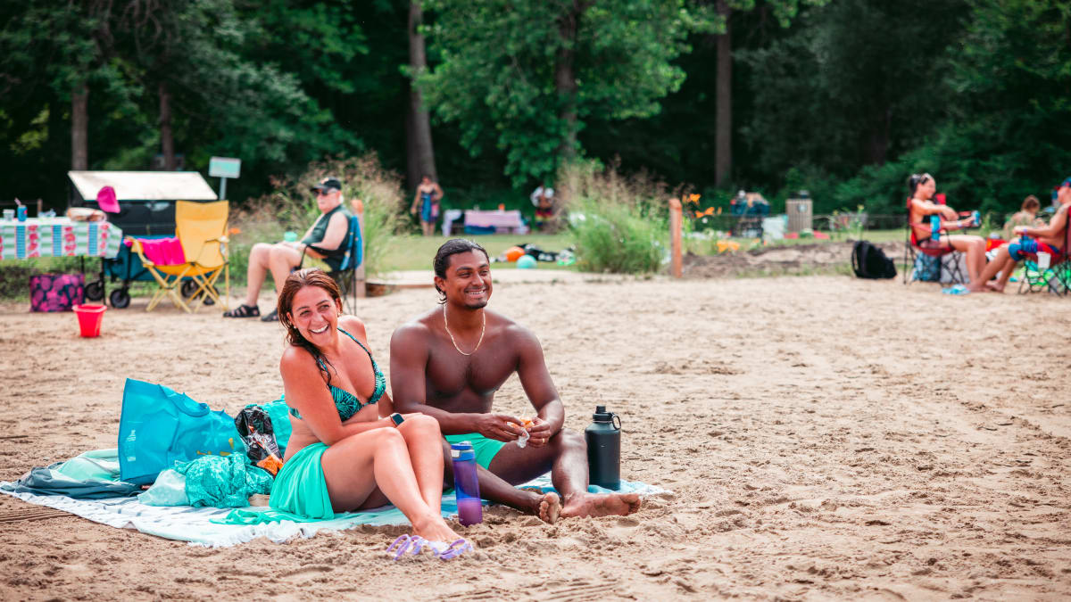 Happy-looking couple sitting on a beach towel.