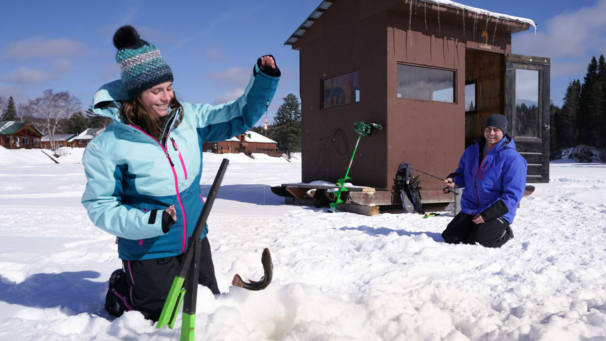 Couple en train de faire de la pêche sur glace par une journée ensoleillée.