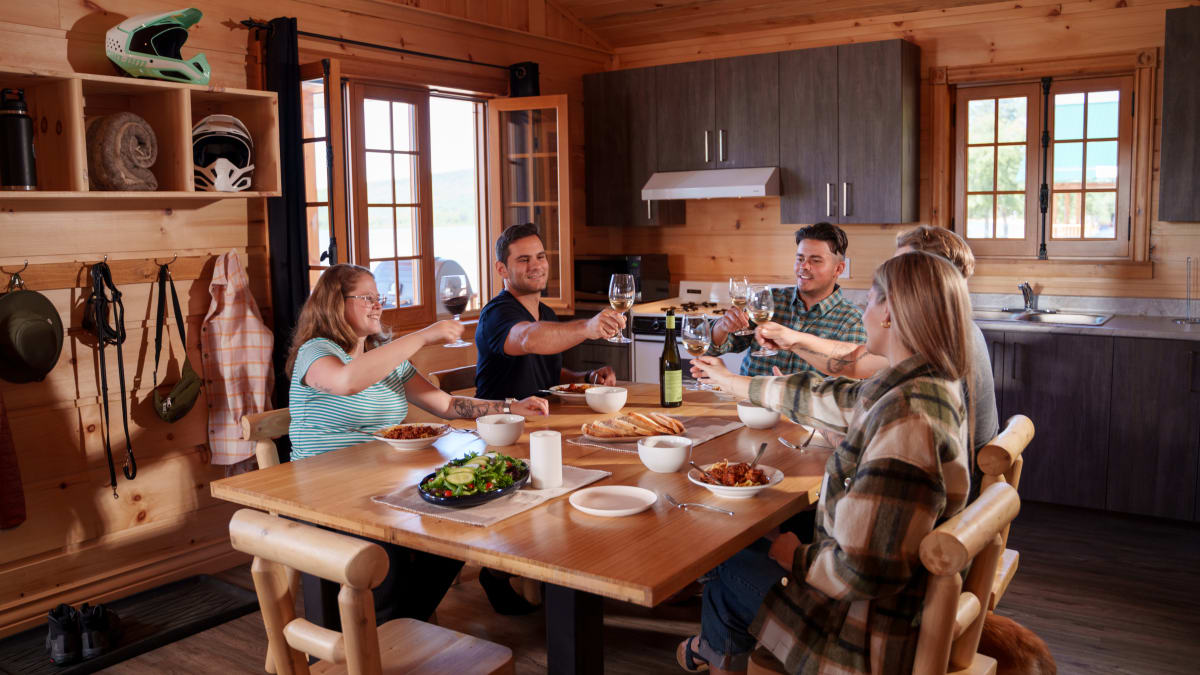 Groupe de convives autour d'une table à l'intérieur d'un chalet en bois.