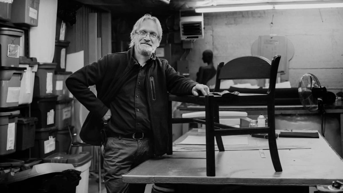 Woodwroking artisan displaying a chair on a workbench.