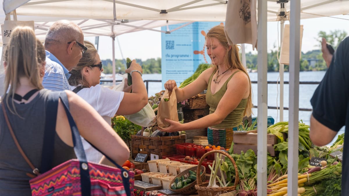 Kiosque de légumes au marché avec clients en ligne et marchande.