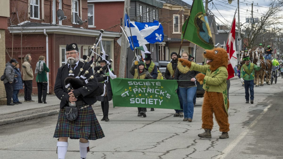 Bagpiper in front of a banner in a parade.