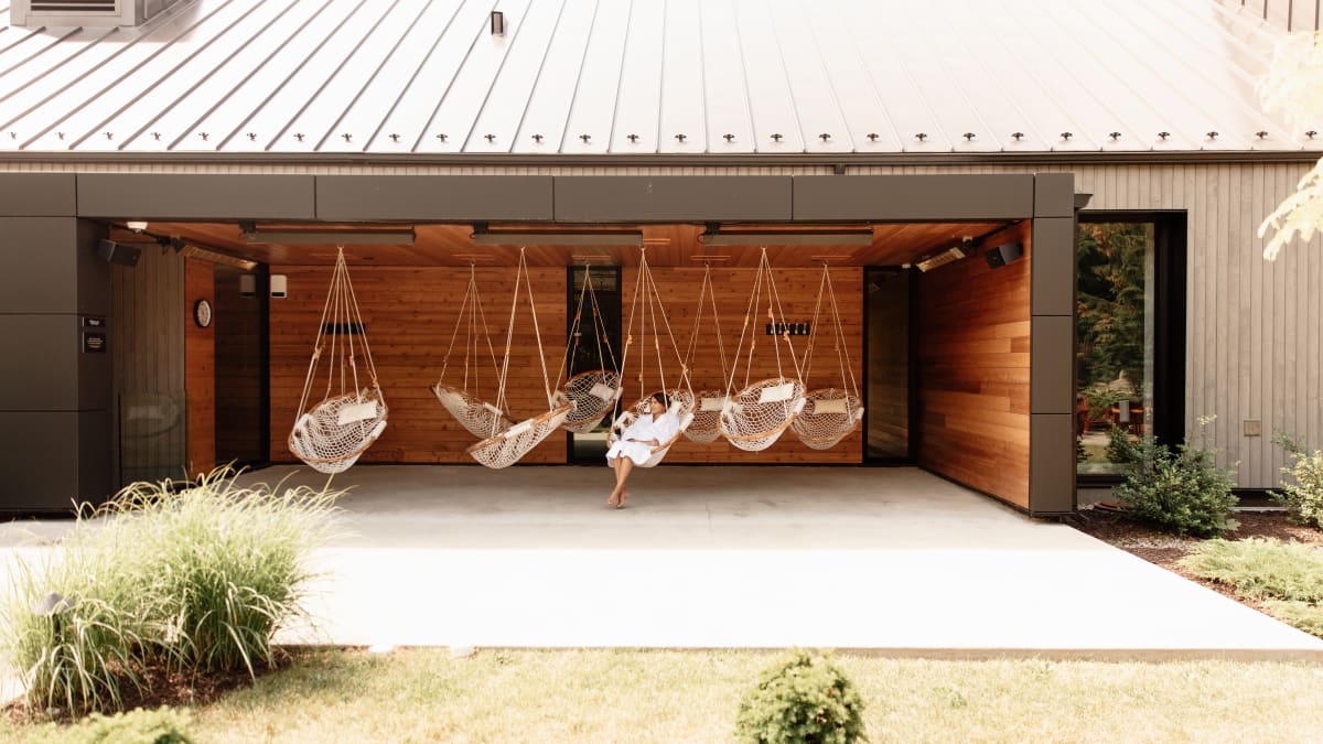 Femme dans un espace de relaxation extérieur, équipé de chaises suspendues.