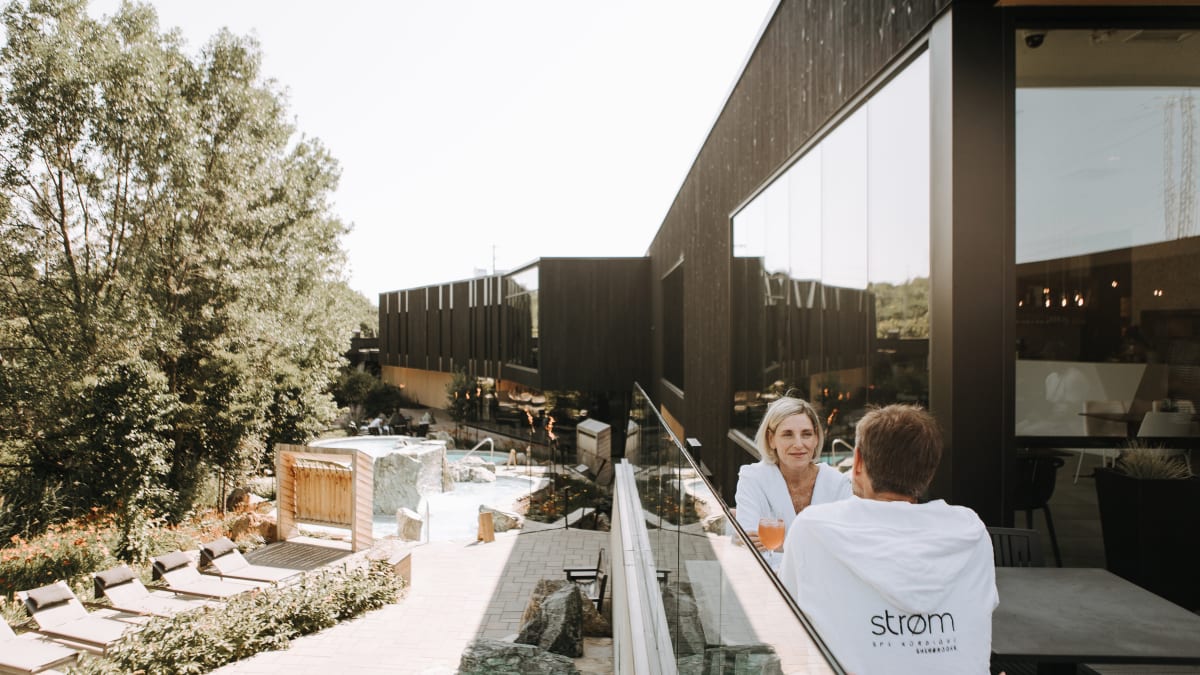 Couple installé sur la terrasse extérieure du restaurant du spa, qui donne sur les installations thermales.