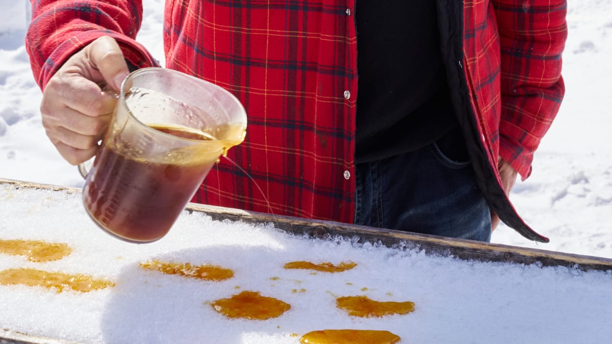 Plan rapproché d'un homme versant du sirop d'érable sur la neige.