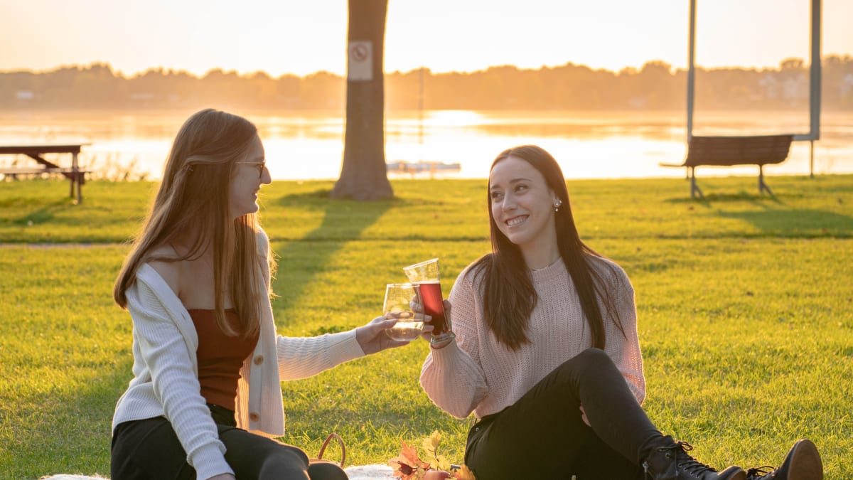 Deux jeunes femmes trinquent et partagent un pique-nique au bord de l'eau.