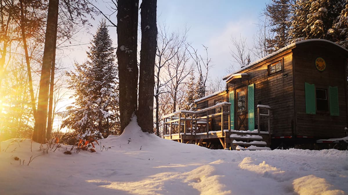 Mini-chalet dans un paysage enneigé sous une luminosité naturelle dorée.