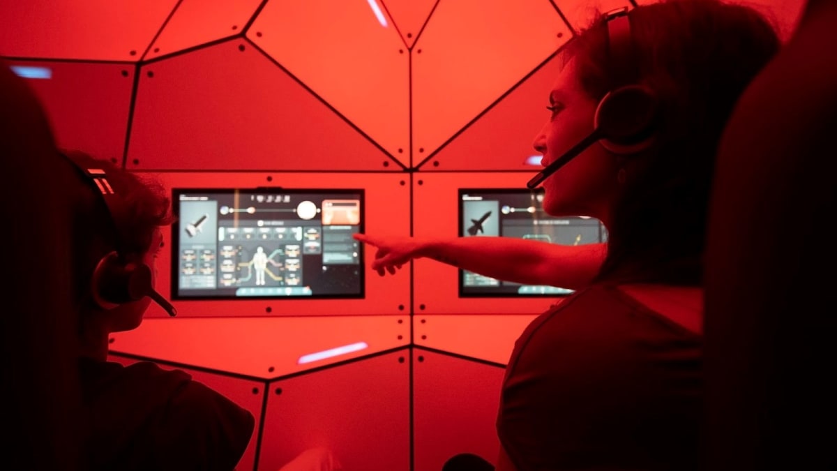 Mother and son wearing headphones sitting in front of screens at the space exhibit.