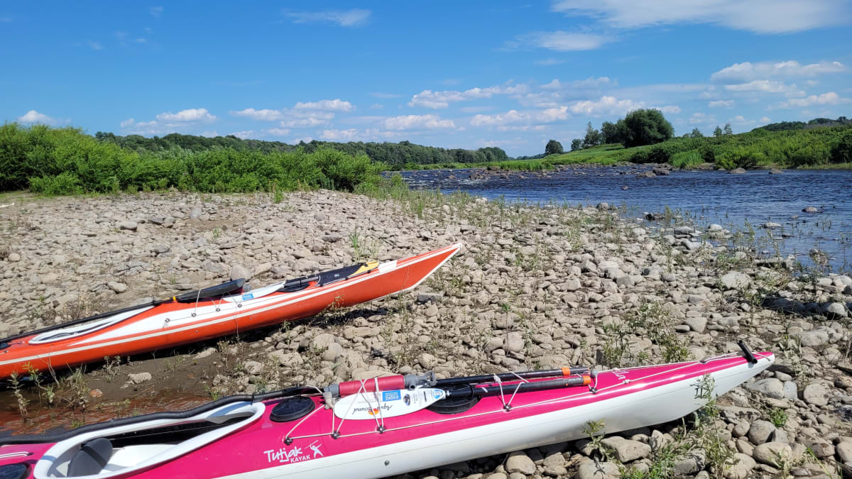 Deux kayaks sur la rive d’un cours d’eau.