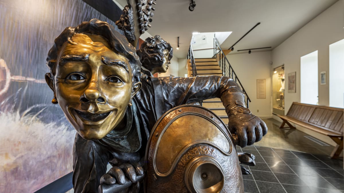 Gros plan sur une oeuvre en bronze qui représente une personne souriante.