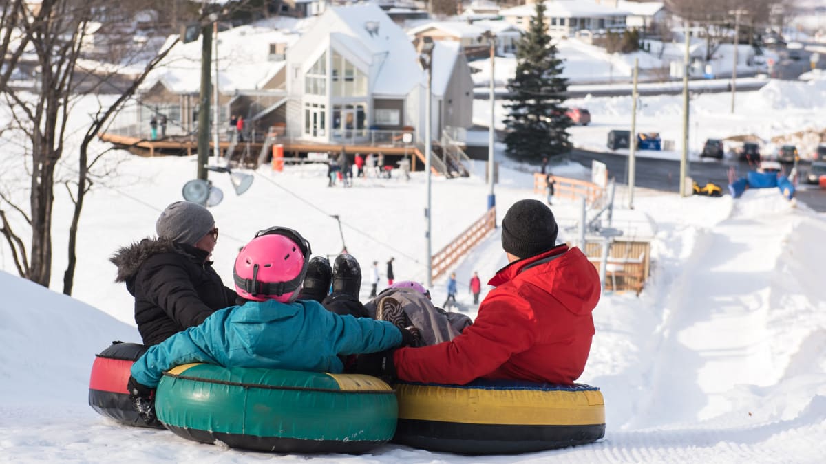 A family tubing down a snowy hill