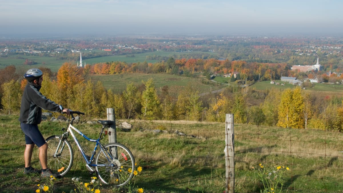 Man with a bike admiring the view of the town of Arthabaska in the fall.