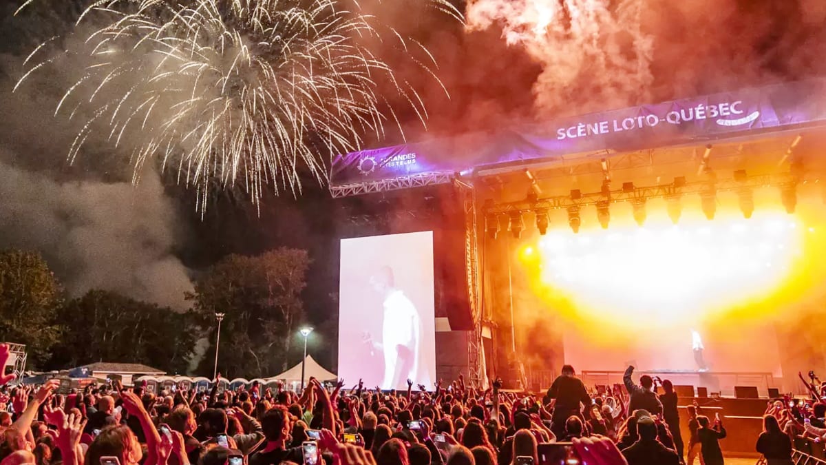 Foule devant une scène dans un festival avec feux d'artifice.