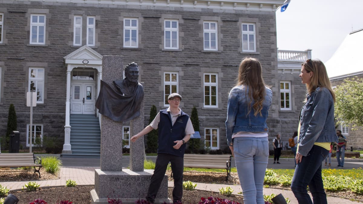 Guide interprète avec deux touristes devant un monument historique