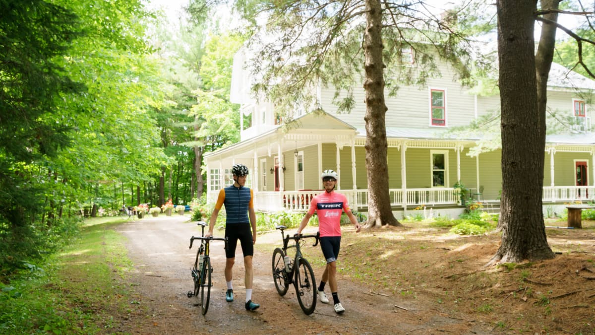Deux cyclistes marchant dans une allée de gravelle d'une grande maison.