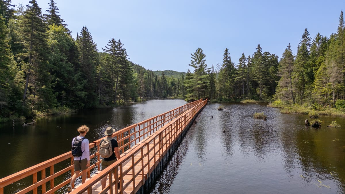 Longue passerelle de bois passant au dessus d'un lac au Parc ECO Laurentides