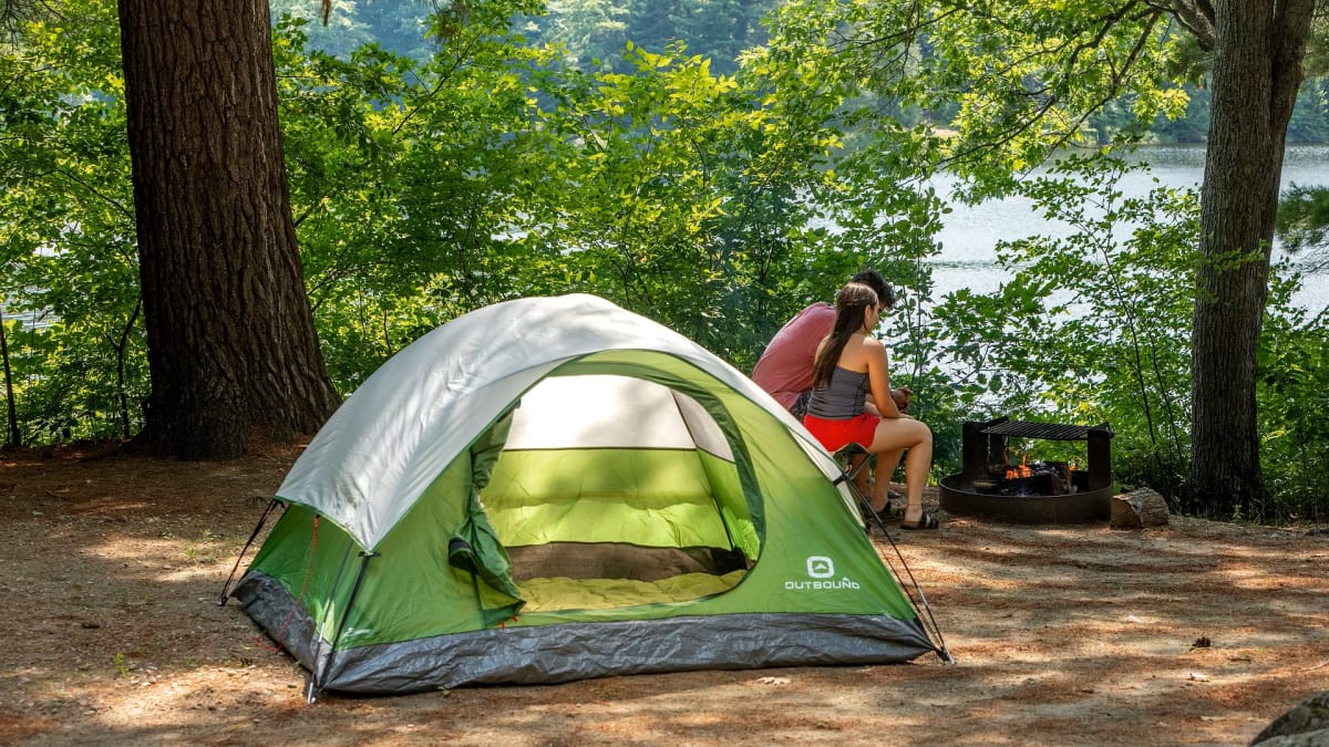 Terrain de camping avec une tente et un couple.