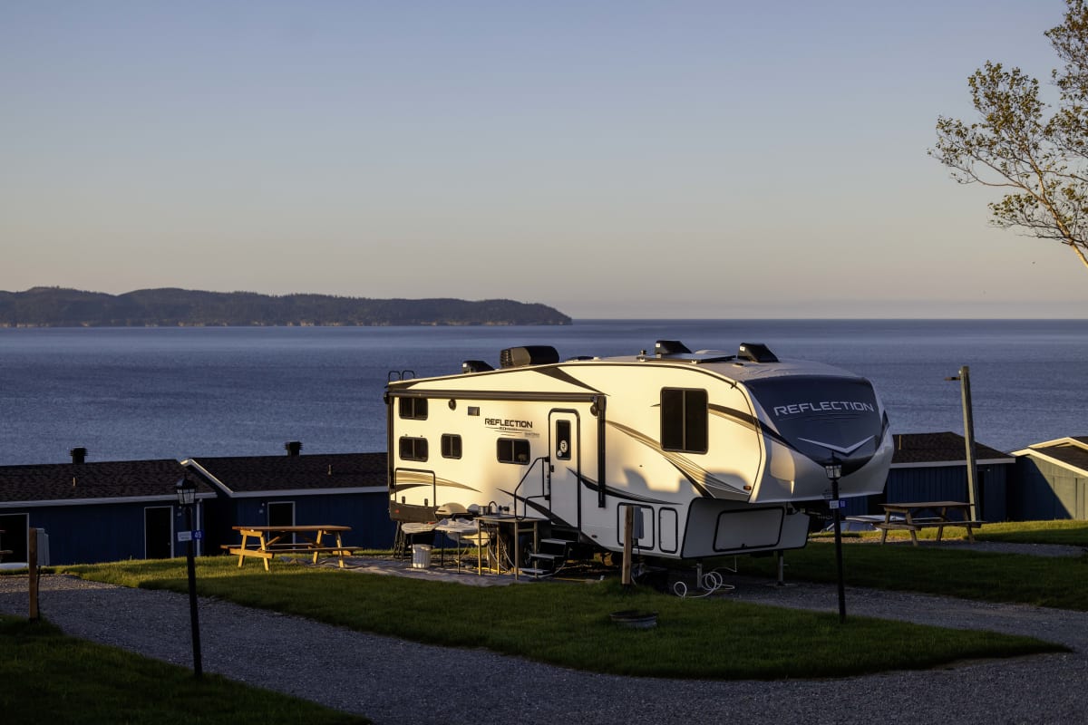 A trailer parked at a campground with a view of the water.