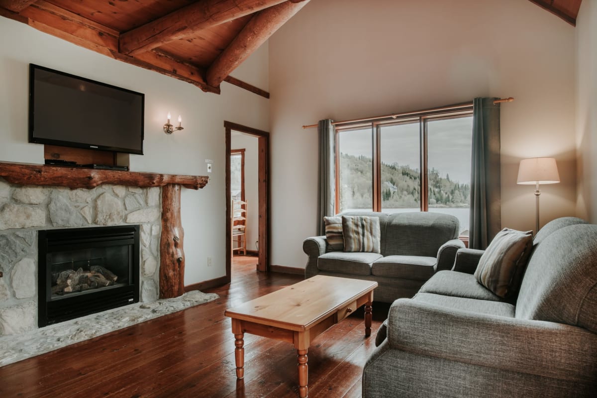 Living room with sofas and a fireplace in one of the Chalets Royal Laurentien.