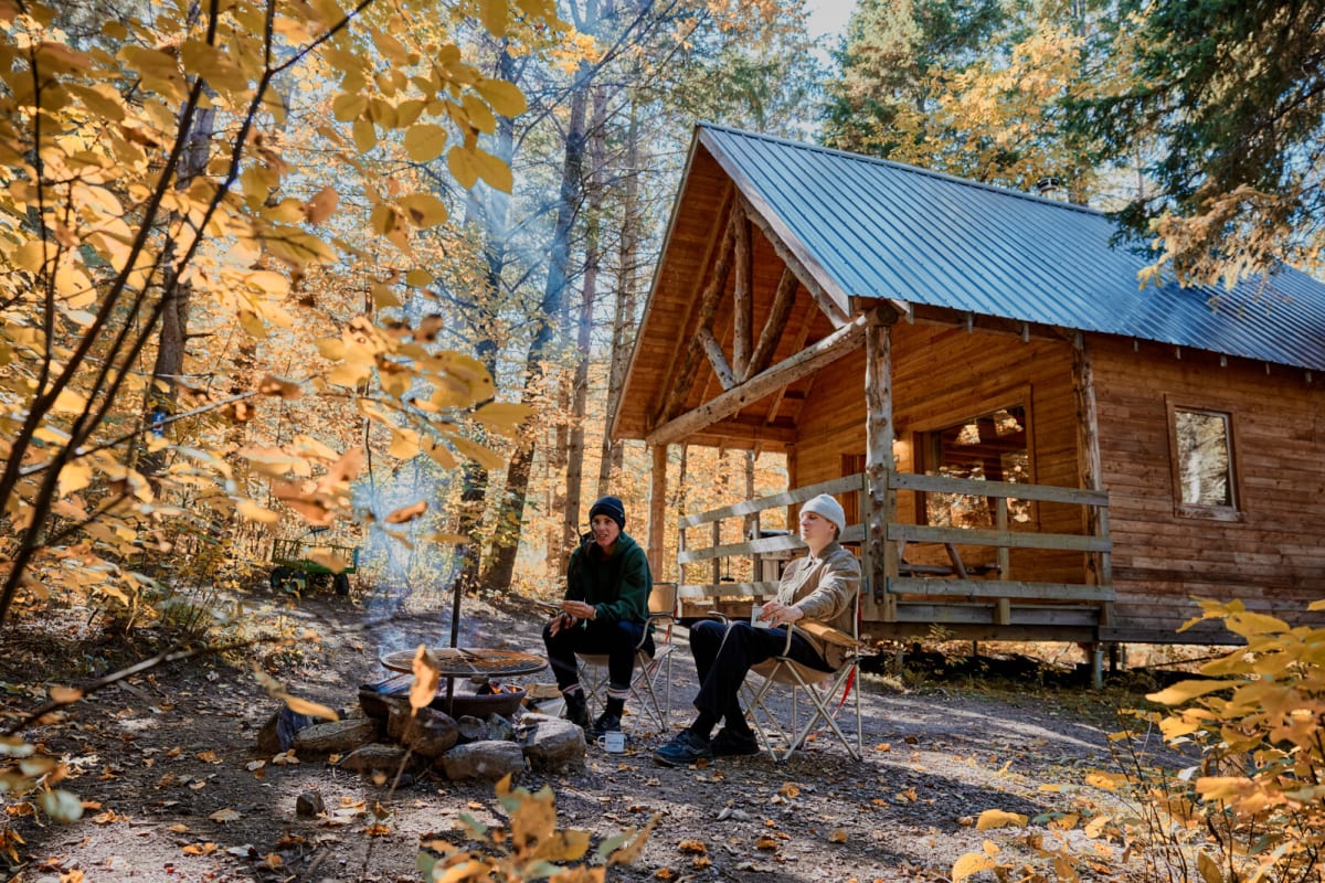 Couple in front of a Huttopia Sutton cabin in autumn