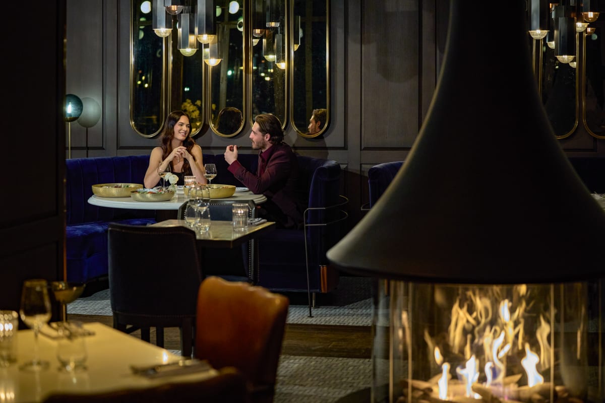 Couple in a restaurant at Fairmont Tremblant, with a fireplace in the foreground