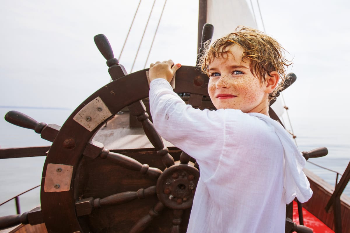 Boy behind the wheel of a ship.