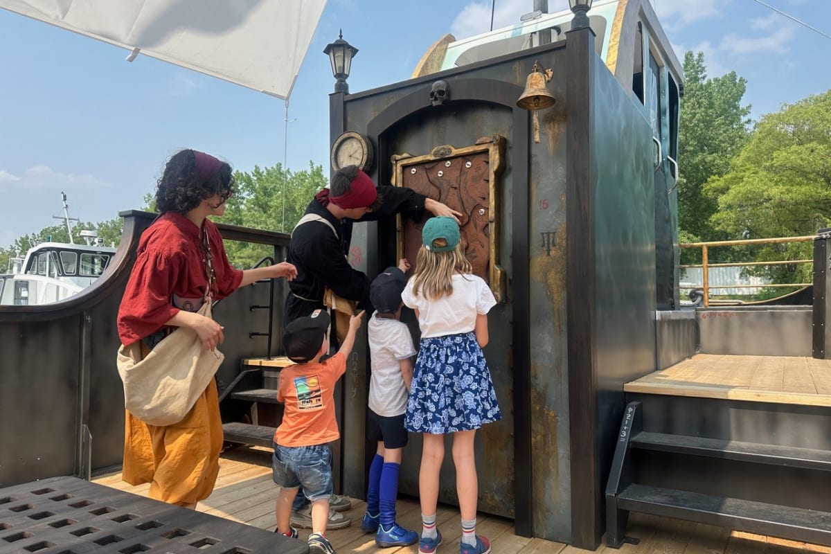 Group of kids and presenters in costumes on a pirate ship.