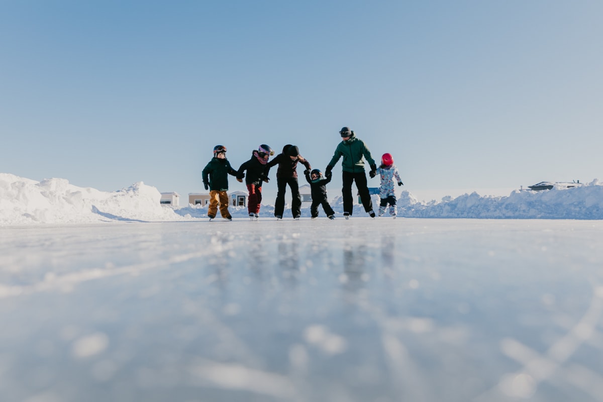 Group of adults and children skating at the Village sur glace.