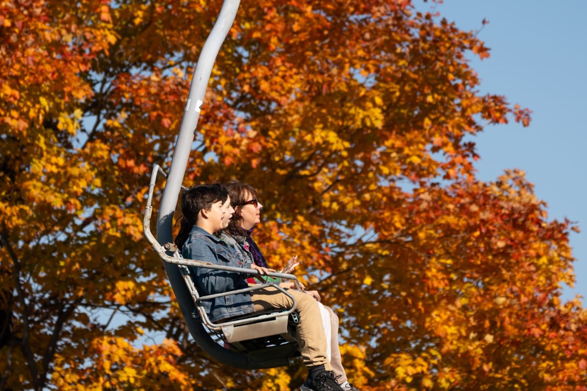 Two adults on a ski lift at Ski Saint-Bruno in the fall.