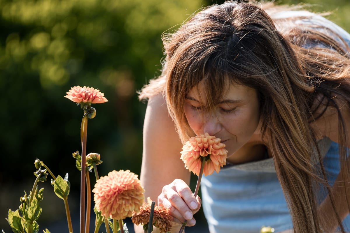 A teenage girl smelling a flower. 