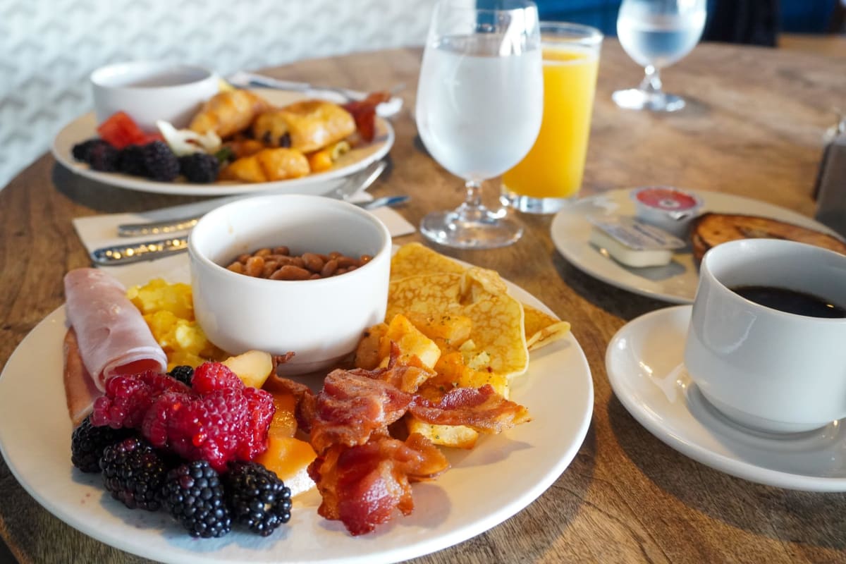 Deux assiettes déjeuner remplies de fruits, bacon et patates. 