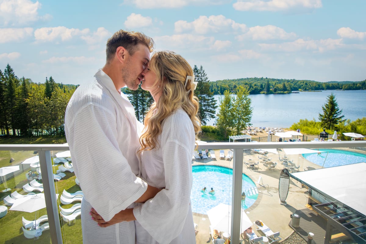 Couple s'embrassant sur un balcon avec la vue sur le lac et le spa - Estérel Resort