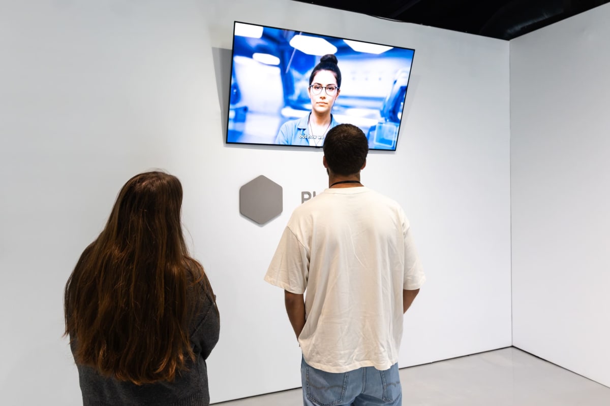 deux personnes en train de regarder une vidéo explicative durant l'Expérience Black Mirror.