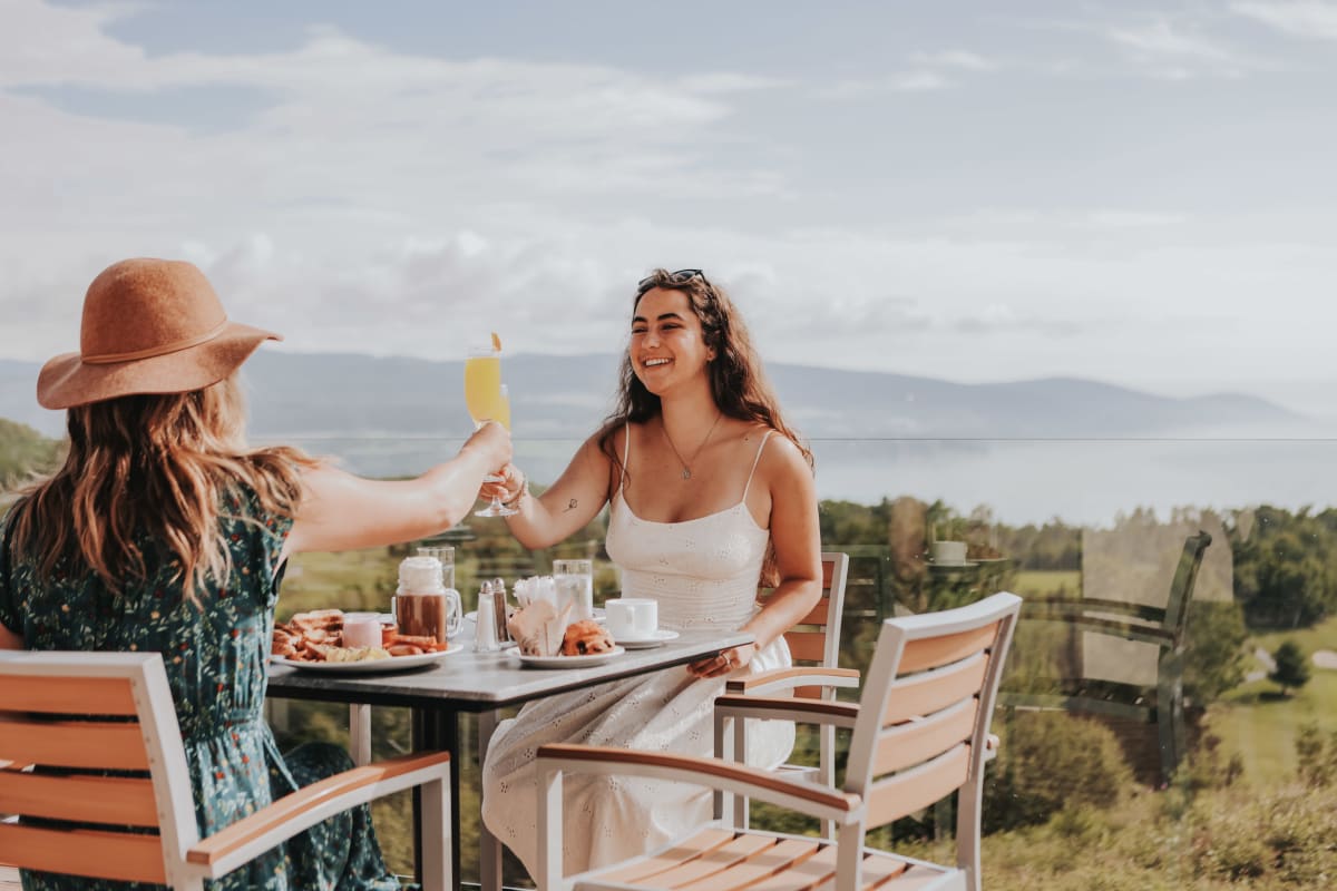 Two women on a sunny terrace, raising a toast.