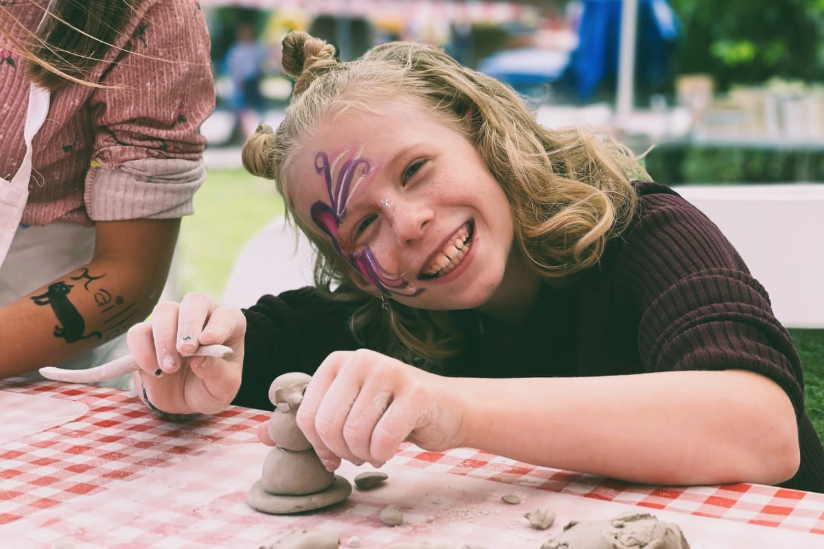 Jeune fille souriante sculptant à l'argile. 