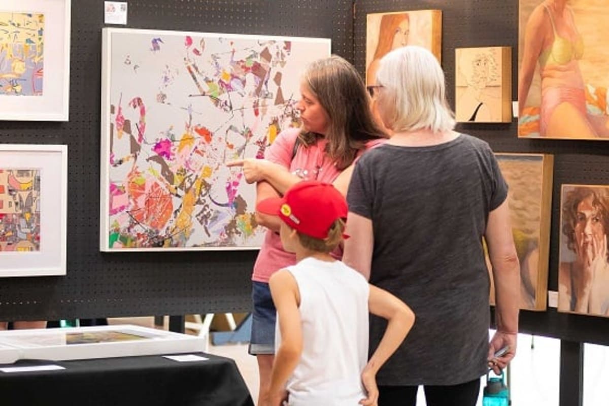Femmes et jeune enfant regardant des toiles.